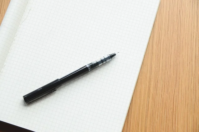 Precalculus: A pen on a grid notebook, ready for writing or calculations.