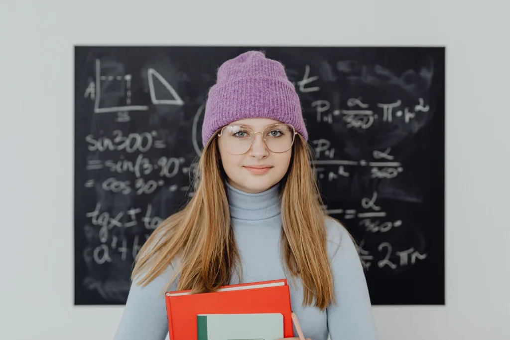 A student in front of a blackboard with math equations and diagrams.