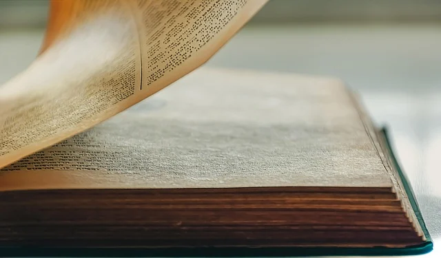 An old book with pages being turned, showing text.