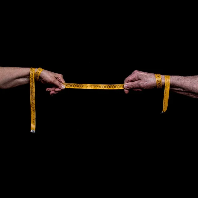 Two hands holding a yellow measuring tape to measure distance