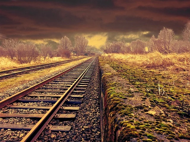 Railroad tracks stretching into the horizon under a stormy sky