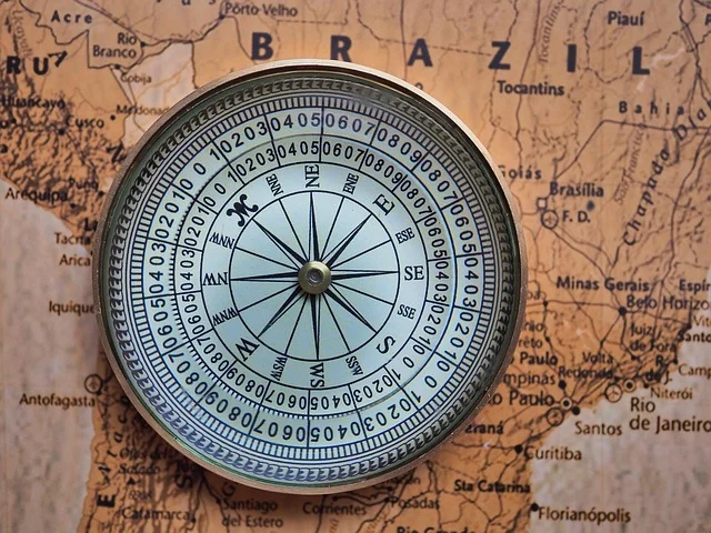 A circular brass compass lying on a vintage map