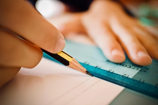 Velocity formula: A hand using a pencil and ruler to draw lines on paper.