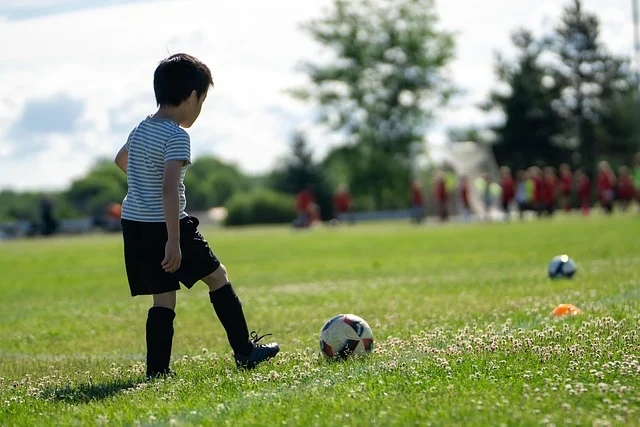 A young boy on a soccer field about to kick a ball.