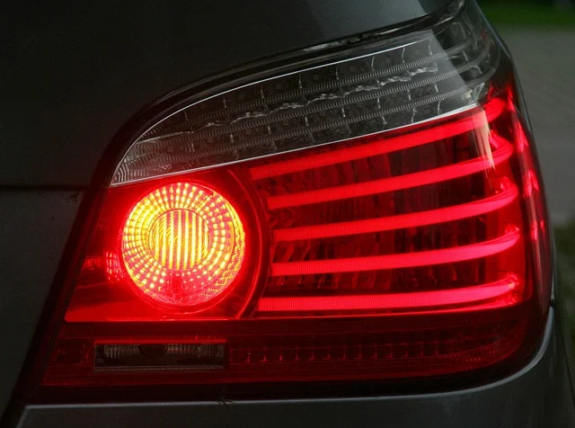 A car's illuminated red brake lights and amber turn signal.