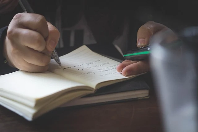 A person writing in a notebook, possibly solving problems.