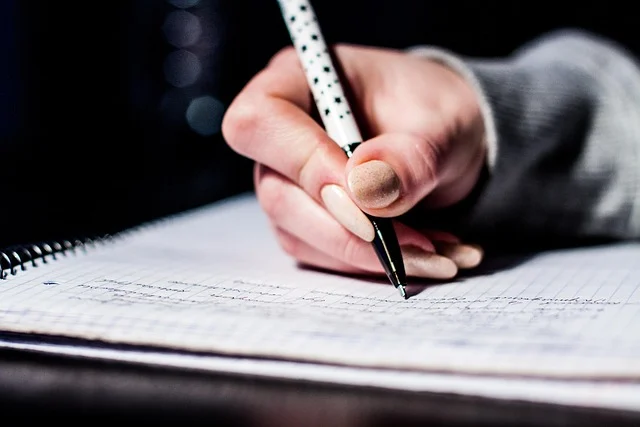 A person's hand writing in a notebook with a pen.