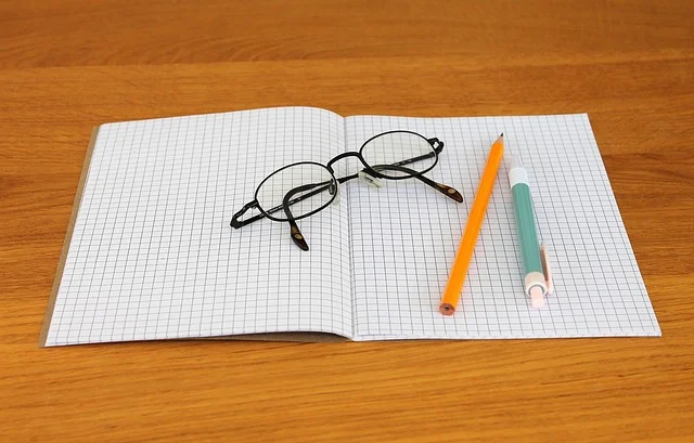 An open grid notebook with glasses, a pencil, and a pen