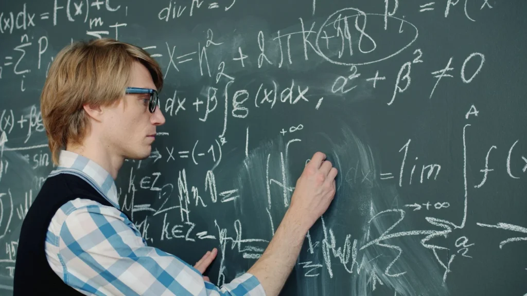 A man writing complex math equations on a blackboard.