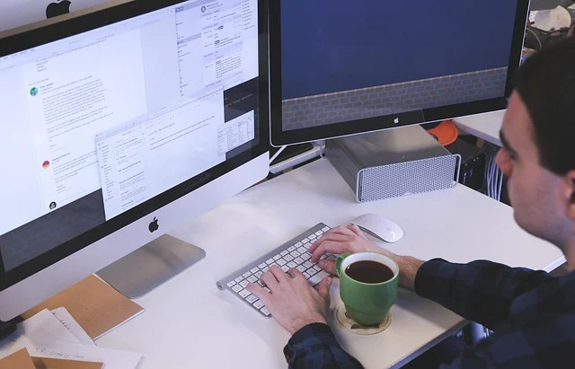 Compound interest formula: A person working at a desk with two computer monitors and coffee