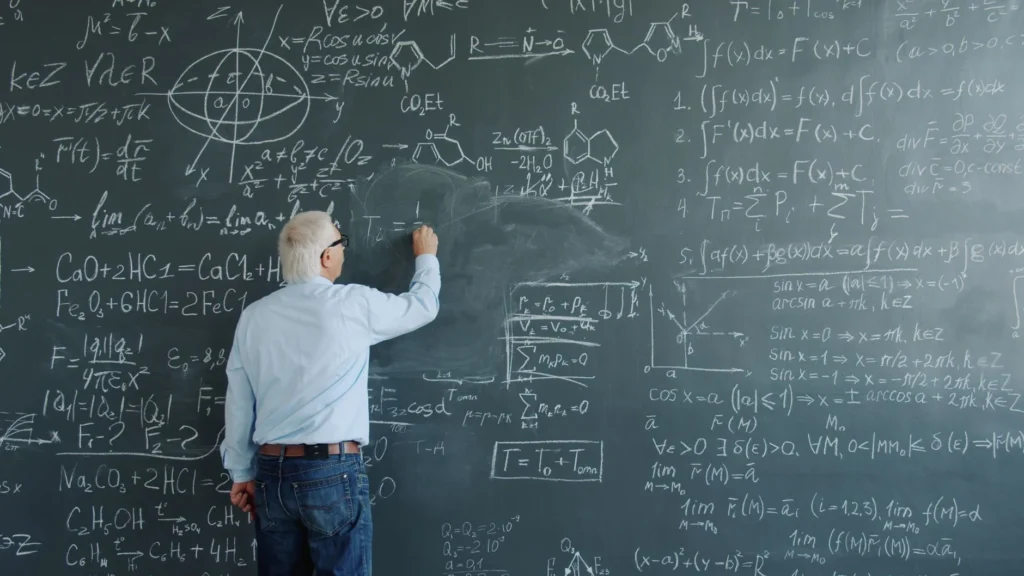 A professor writing various mathematical and chemical equations on a blackboard.