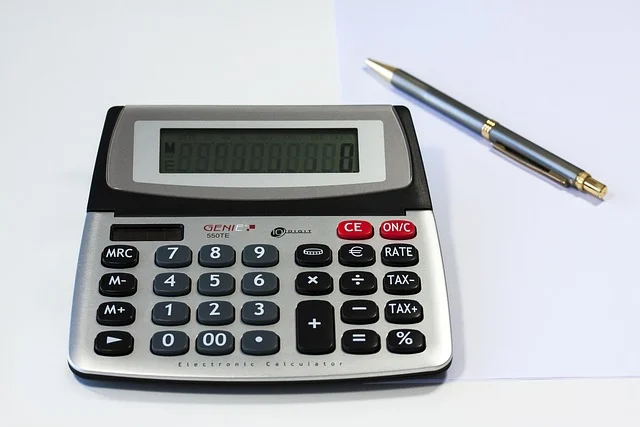 A calculator and a pen on a white surface, ready for calculations.
