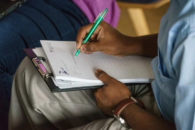 A person writing on a notepad attached to a clipboard