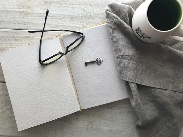Open blank book with eyeglasses, a small key, and coffee mug