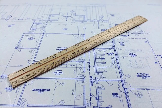A ruler on a blueprint, showing architectural plans and measurements.