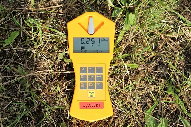 A yellow Geiger counter measuring radiation on grass