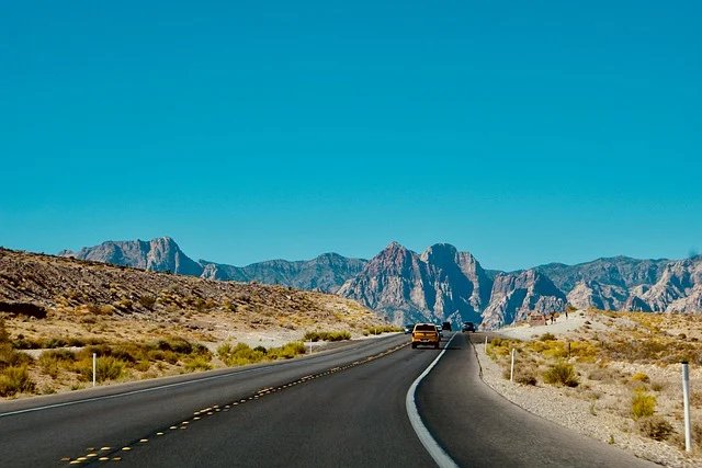 Cars driving on a desert road with mountains in the background