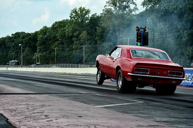 A red drag racing car accelerating rapidly, lifting its front wheels.