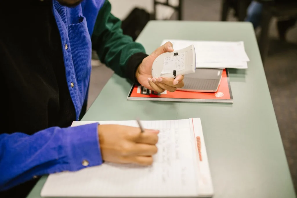 Distance formula: A student writing in a notebook while holding a calculator