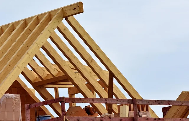 Wooden roof trusses under construction against a blue sky.