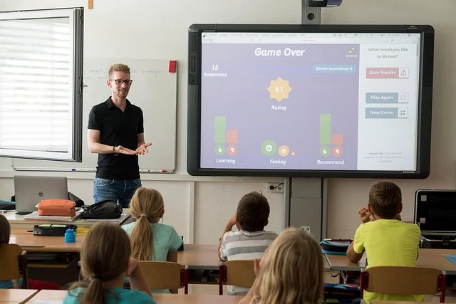 A teacher presenting to students in a classroom with a smartboard