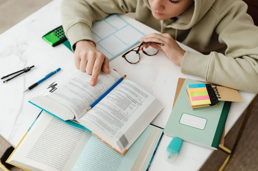 A student studying a textbook with notes and a calculator on a desk.